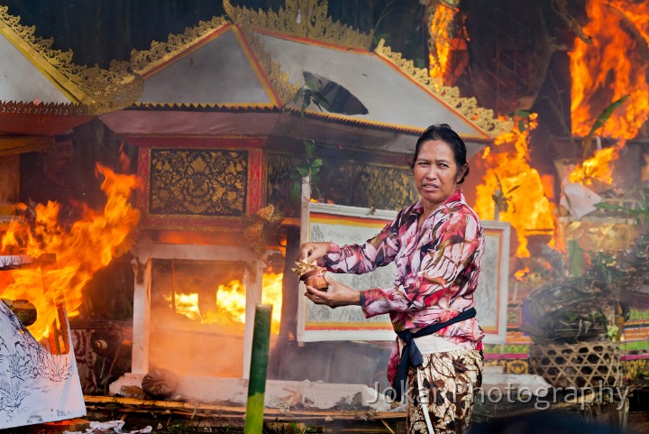 Bangli_cremation_20100829_130.jpg - 9. BANGLI CREMATION #1 - Turning her head away from the heat,  a woman prepares to put one last offering into the flames at a mass cremation ceremony in Bunut, Bangli Regency.