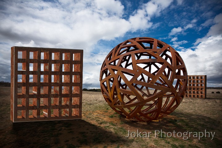 Island_Bend_20111001_011.jpg - Homage to Neversphere.  The sphere can be found beside the main Cooma-Berridale road, near the junction with Frampton Road. It was constructed by South Coast sculptor Richard Moffatt from metal left over after construction of the SkiTube.  From the Snowy River Echo (4 May 2011): The concept behind the sculpture centres on the complex and binding interconnections between the people of the Shire. “In the Snowy River Shire, there is a very small community spread over a vast area of land. I’ve created this form that basically represents crossroads or lines of communication. The surface of the sphere is indicative of the lines of communication that run all through this vast landscape and are so vital for the community,” Richard said.The sculpture was commissioned by the local Shire Council to provide a ‘gateway’ to the Snowy River Shire. It also provides a gateway into my own photographic project, as the negotiation of names (for places and things) is a theme which recurs throughout the series.The artist called the work ‘Neversphere’, and reportedly didn’t want a name that could constrain a viewer’s own interpretation of the work.  One Councillor sought to have the sculpture remain nameless. However, after considering some 38 public submissions, in June 2011 the Snowy River Shire Council selected the name ‘Snowyriversphere’. Other proposed names included ‘Merino Country’, ‘Paradigm Sphere’, and ‘The Big Giant Ball’. The two square grids exist only in virtual space.